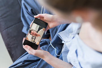 Image showing Woman at home relaxing on sofa couch using social media on phone for video chatting with her loved ones during corona virus pandemic. Stay at home, social distancing lifestyle.