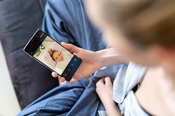 Image showing Woman at home relaxing on sofa couch using social media on phone for video chatting with her loved ones during corona virus pandemic. Stay at home, social distancing lifestyle.