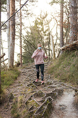 Image showing Corona virus, or Covid-19, is spreading all over the world. Portrait of caucasian sporty woman wearing a medical protection face mask while running in nature.