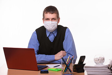 Image showing Office specialist in a protective medical mask sits at a desk and looks into the frame