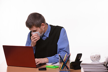 Image showing Office worker in medical mask sneezes at workplace