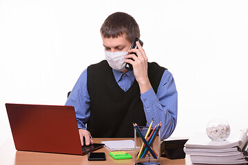 Image showing Clerk in a medical mask talking on the phone and working in a computer