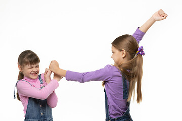 Image showing One older girl pounds another girl with her fists