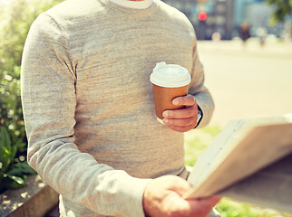 Image showing senior man with coffee reading newspaper outdoors