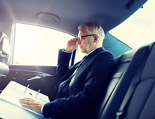 Image showing senior businessman with papers driving in car