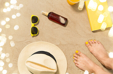 Image showing feet, hat, shades, sunscreen and book on beach