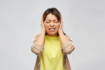 Image showing stressed asian woman closing ears by hands