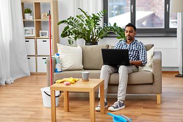 Image showing man with laptop computer after home cleaning