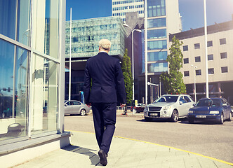 Image showing senior businessman walking along city street