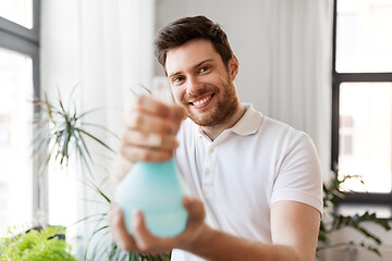 Image showing man spraying houseplants with water at home