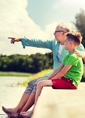 Image showing grandfather and grandson sitting on river berth