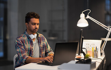 Image showing creative man with laptop working at night office