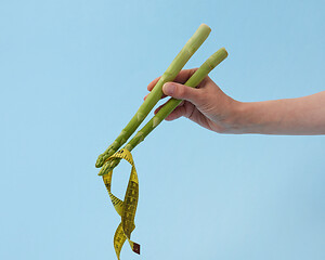 Image showing Asparagus spears in a woman\'s hand holding yellow measuring tape.