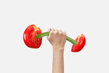 Image showing Woman hand holds sport barbell made from natural cut tomatoes.