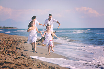 Image showing happy family playing with dog on beach