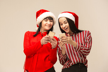 Image showing Happy family in Christmas sweater posing on a red background in the studio.