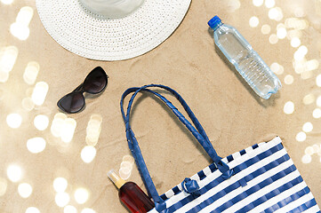 Image showing beach bag, sunscreen, sunglasses and hat on sand