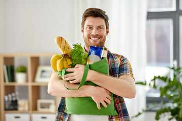 Image showing smiling young man with food in bag at home