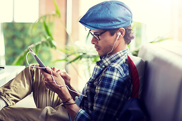 Image showing man with tablet pc and earphones sitting at cafe