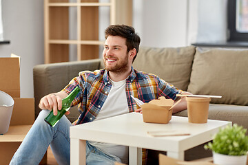 Image showing smiling man drinking beer and eating at new home