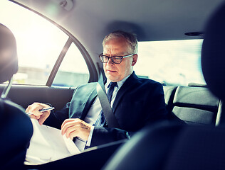 Image showing senior businessman with papers driving in car