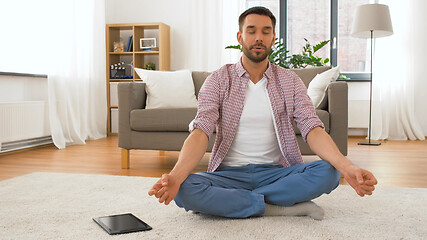 Image showing man with tablet computer meditating at home