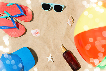 Image showing cap, flip flops and shades and beach ball on sand