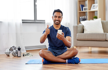 Image showing indian man with smartphone on exercise mat at home