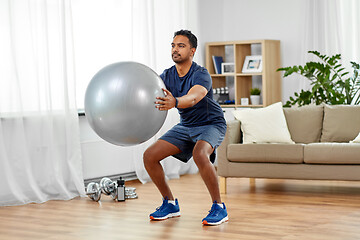 Image showing man exercising and doing squats with ball at home