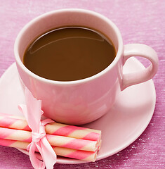 Image showing Mug of freshly brewed coffee and some strawberry cookie sticks 