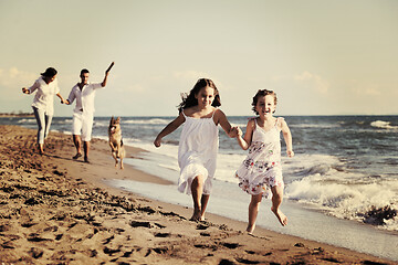 Image showing happy family playing with dog on beach