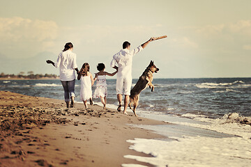 Image showing happy family playing with dog on beach