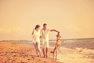 Image showing happy family playing with dog on beach