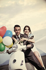 Image showing just married couple on the beach ride white scooter