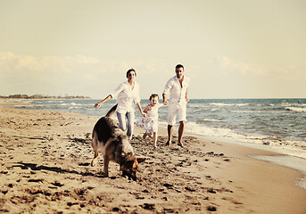 Image showing happy family playing with dog on beach