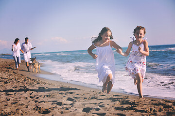 Image showing happy family playing with dog on beach