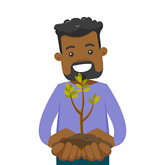 Image showing African-american man holding green plant in soil.