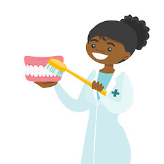 Image showing Young dentist cleaning jaw model with toothbrush.