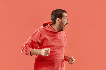 Image showing The young emotional angry man screaming on coral studio background