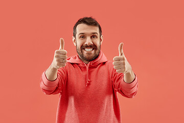 Image showing The happy businessman standing and smiling against coral background.