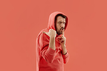 Image showing The young man whispering a secret behind her hand over coral background