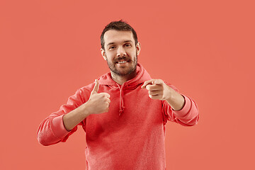 Image showing The happy businessman standing and smiling against coral background.