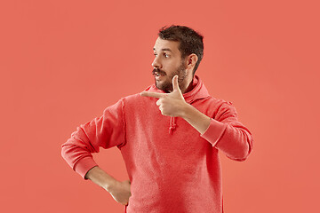 Image showing The young attractive man looking suprised isolated on coral