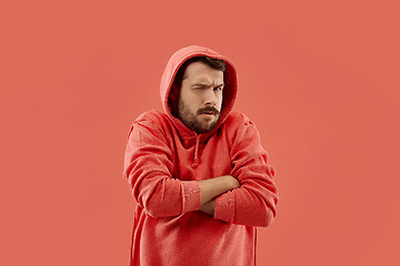 Image showing Suspiciont. Doubtful pensive man with thoughtful expression making choice against coral background