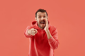 Image showing Isolated on coral young casual man shouting at studio