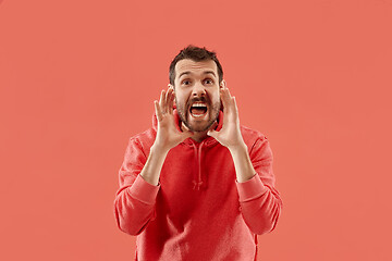 Image showing Isolated on coral young casual man shouting at studio