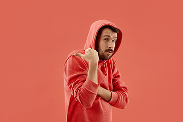 Image showing The young man whispering a secret behind her hand over coral background