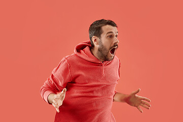 Image showing The young attractive man looking suprised isolated on coral