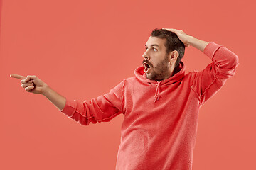 Image showing The young attractive man looking suprised isolated on coral