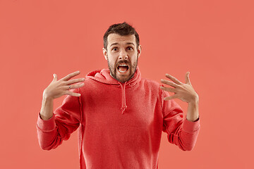 Image showing The young attractive man looking suprised isolated on coral